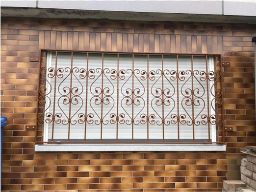 Schmiedeeisernes Fenstergitter an einer Klinkerfassade